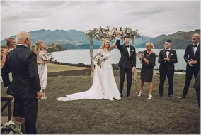 Bride and groom raise their hands in celebration after being pronounced husband and wife in a Michigan outdoor wedding.