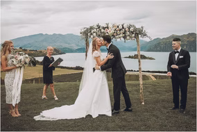 Newlyweds share their first kiss under a floral wedding arch at a Michigan outdoor ceremony.