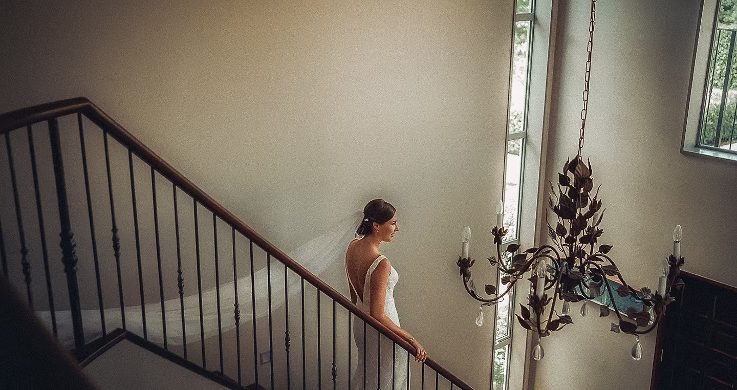 Overhead photo of bride standing in sunlit foyer holding white bouquet before first look at a Michig