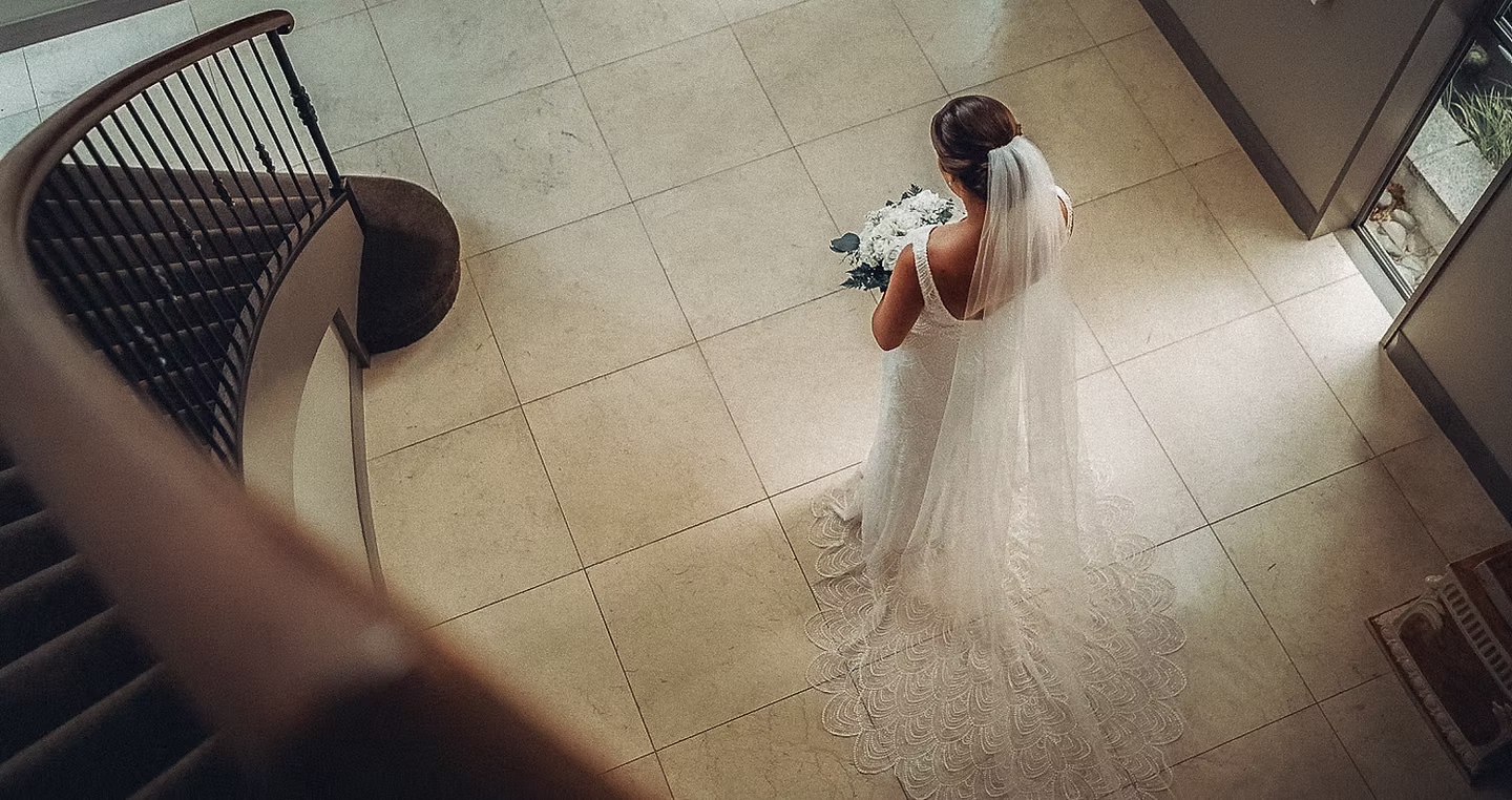Bride walking down elegant staircase with cathedral veil at Ann Arbor wedding venue